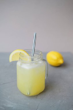 Meyve suyu limon gri bir arka plan üzerinde cam kavanozda
