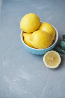 Gri bir arka plan üzerinde mavi bir kase taze limon