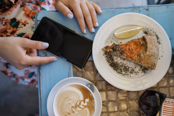 Manos Mujer Con Teléfono Pastel Verduras Capuchino Mesa Café — Foto de Stock