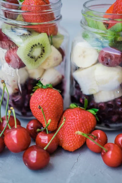 新鲜的切片水果在一个罐子 樱桃香蕉和蓝莓的灰色背景 有用小吃 — 图库照片