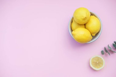 Pembe bir arka plan üzerinde mavi bir kase taze limon