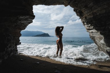 Arkadan Görünüş kırmızı mayo deniz kenarında sahilde poz içinde genç esmer kadın. İyi sağlıklı yaşam sıklıkta olmak