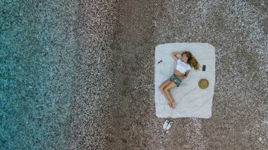 Bir kadın en iyi hava görünümünü bir plaj havlusu üzerinde şort ve yelek plajında. Uçak fotoğraf