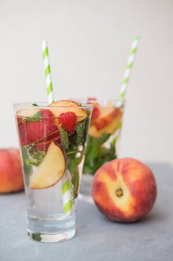 Ev yapımı buzlu limonata veya olgun şeftali ve ahududu çay. Gri arka plan. 