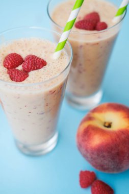 Şeftali smoothies süt (yoğurt), ahududu ve çizgili payet ile. Mavi arka plan. Alan üst görünüm Kopyala