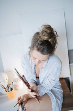 Kadın sanatçı el ressam fırçalar çizim ve tuval önünde ile. Sanatçı studio iç. Süreç içinde sanat atölyesi.