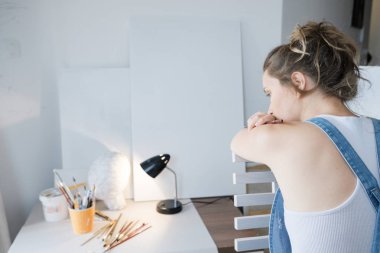 İlham bulmak için. Üzgün kadın ressam tuval ve çizim önünde. Sanatçı studio iç. Süreç içinde sanat atölyesi.