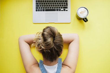 Dizüstü bilgisayar ve kahve sarı masada yanında uyuyan sarışın kadın. Üstten görünüm, düz lay