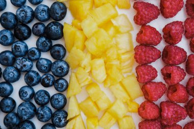 «Ana sayfa» gökkuşağı renkleri, ananas, böğürtlen, yaban mersini ve ahududu nane ile sağlıklı meyveleri görünümünü kapalı beyaz üzerine tablo, düz yatıyordu