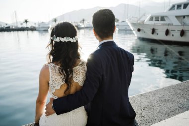 Çiftin arkadan görünüm tekneler ve deniz arka plan üzerinde oturur. Romantik tarih