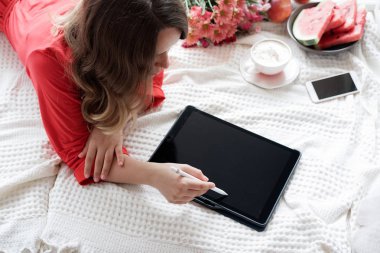 Tablet üzerinde yatak ve içecekler kahve pencere arka plan üzerinde kırmızı bir elbise içinde güzel sarışın kadın 