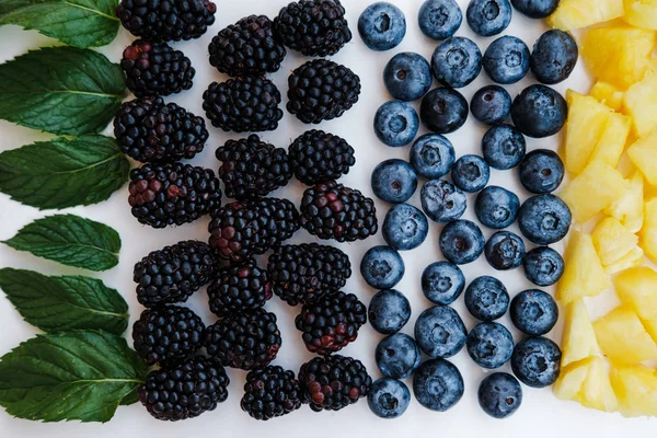健康浆果的顶级视图彩虹色 蓝莓和覆盆子与薄荷在白色的桌子上 — 图库照片