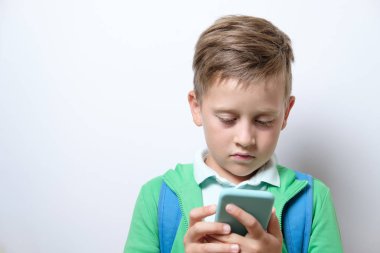 Mavi sırt çantası ve beyaz bir arka plan Akıllı telefon ile sevimli bir öğrenci portresi