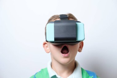 Sevimli öğrenci kolları olan sanal gerçeklik kask giyiyor mavi sırt çantası ile ileri beyaz bir arka plan üzerinde gerilmiş