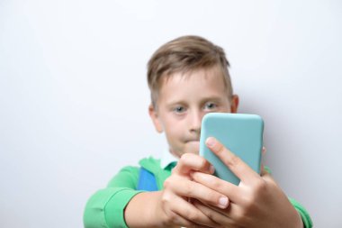 Mavi sırt çantası ve beyaz bir arka plan Akıllı telefon ile sevimli bir öğrenci portresi