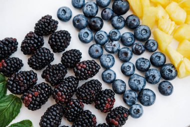 «Ana sayfa» gökkuşağı renkleri, ananas, böğürtlen, yaban mersini ve ahududu nane ile sağlıklı meyveleri görünümünü kapalı beyaz üzerine tablo, düz yatıyordu