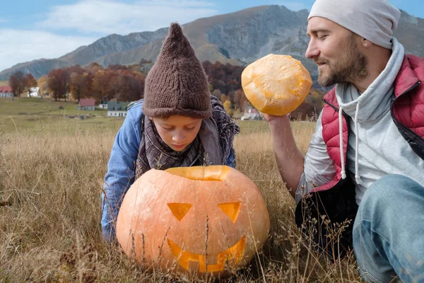 自然背景を父とハロウィンのカボチャ彫刻帽子でかわいい男の子 — ストック写真