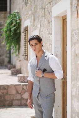 Elbiseli çekici genç moda adam eski şehir yürür.