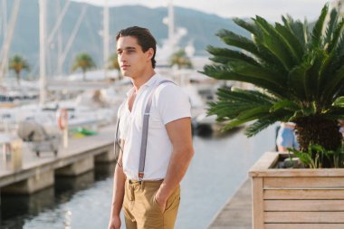 Yatlar ve oteller ile iskele boyunca genç çekici şık adam girer. Erkek model portresi.