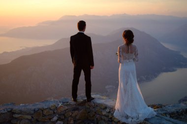Gelin ve damat Günbatımında dağın tepesinde duran arkası