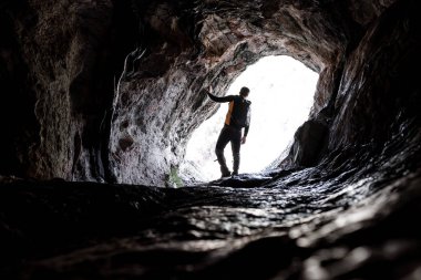 Genç bir mağarada ekipman eylem için hazır tırmanma siyah spor giyim Explorer'da silüeti