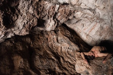 Genç adam bir mağarada yalnız korkularını test ediyor. Atletik vücut, arama, yalnızlık