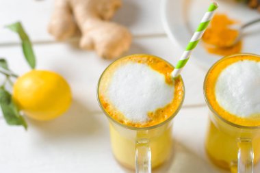 Beyaz tabl üzerinde zerdeçal latte veya gözlük ve limon altın süt üstten görünüm