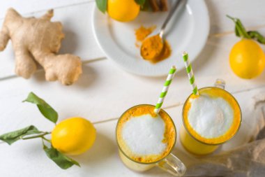 Beyaz tabl üzerinde zerdeçal latte veya gözlük ve limon altın süt üstten görünüm