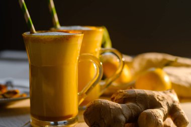 Zerdeçal latte veya gözlük zencefil ve limon beyaz bir tablo ile altın süt