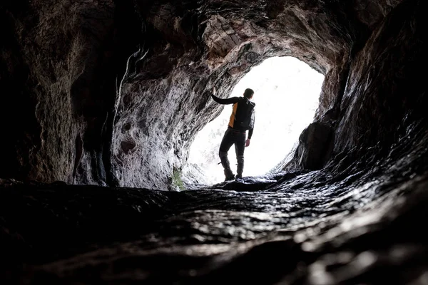 Genç bir mağarada ekipman eylem için hazır tırmanma siyah spor giyim Explorer'da silüeti