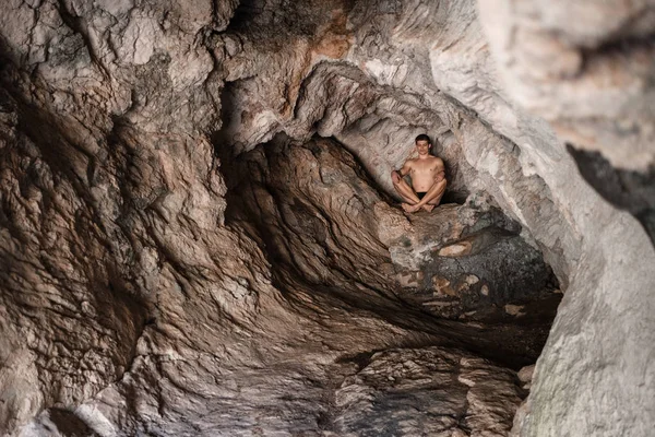 young man in a cave alone is testing his fears. Athletic body, search, loneliness