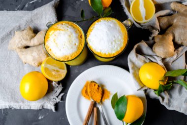 Zerdeçal latte veya gözlük zencefil ve limon siyah bir tablo ile altın süt