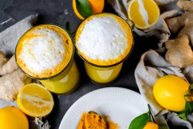 Zerdeçal latte veya gözlük zencefil ve limon siyah bir tablo ile altın süt