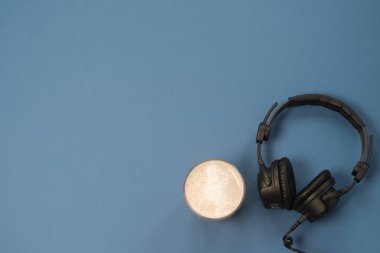 Kulaklık, mikrofon ve kahve mavi bir arka plan üzerinde düz yatıyordu kompozisyonu. Podcast veya webinar kavramı.