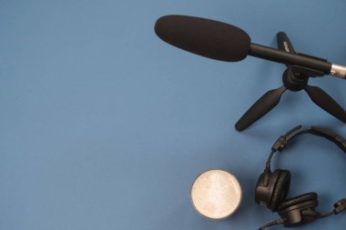 Kulaklık, mikrofon ve kahve mavi bir arka plan üzerinde düz yatıyordu kompozisyonu. Podcast veya webinar kavramı.