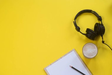Kulaklık, mikrofon ve kahve sarı bir arka plan üzerinde düz yatıyordu kompozisyonu. Podcast veya webinar kavramı.