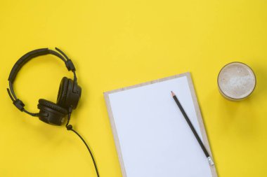 Kulaklık, mikrofon ve kahve sarı bir arka plan üzerinde düz yatıyordu kompozisyonu. Podcast veya webinar kavramı.