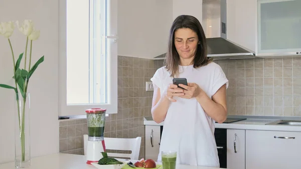 Mladá Žena Bílém Tričku Připravuje Zelený Smoothie Mixér Doma Kuc — Stock fotografie