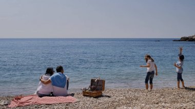 Güneşli bir yaz gününde, deniz kenarında bir kızla aile pikniği. B