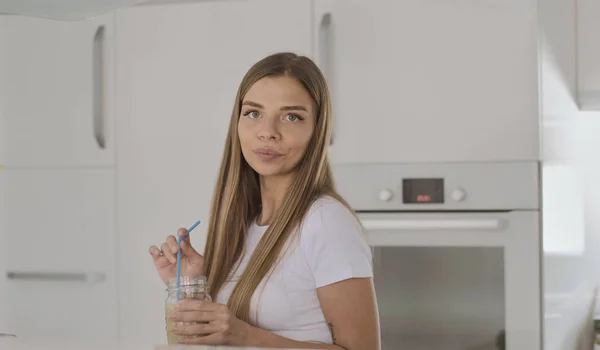 Ung blond kvinna i vit t-shirt dricker fruktsmoothie och dan — Stockfoto