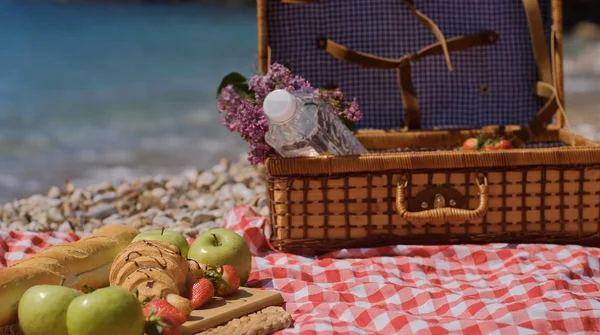 Nahaufnahme eines sommerlichen Picknickkorbs mit Wasser, Obst und Croissant — Stockfoto