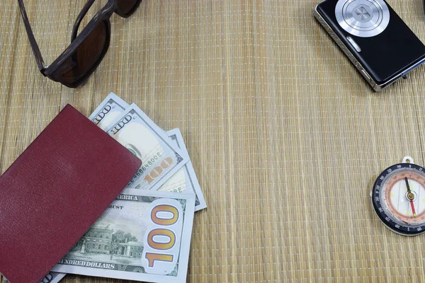 passport with money (dollars) for vacation, camera, glasses and different things on the table