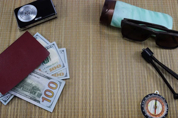 passport with money (dollars) for vacation, camera, glasses and different things on the table