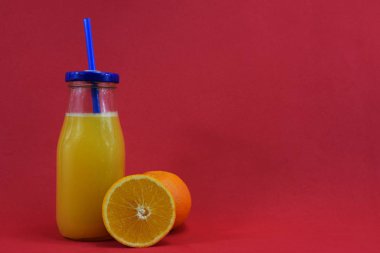 Bir bardak taze aleklin suyu ile ve bir portakal yanında yatıyor.