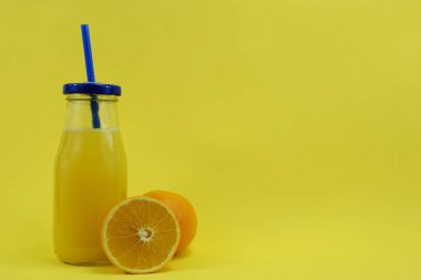 Bir bardak taze aleklin suyu ile ve bir portakal yanında yatıyor.