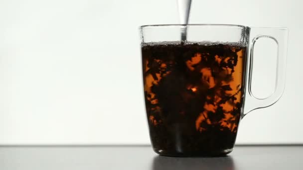 Stirring tea leaves in clear cup of tea — Stock Video