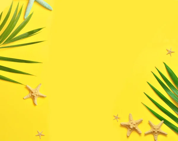 Tropische achtergrond. Palm bomen takken met zeester op gele achtergrond. Reizen. Kopiëren van ruimte. — Stockfoto