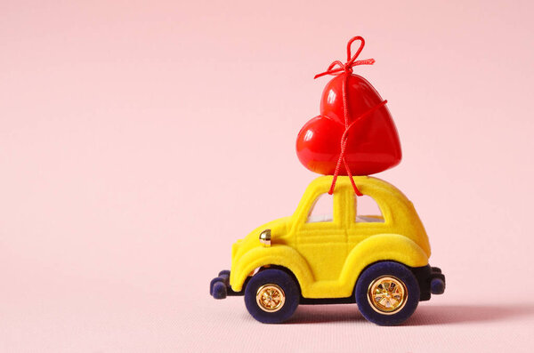 Little yellow beetle car carries a red heart. The concept of Valentine Day.