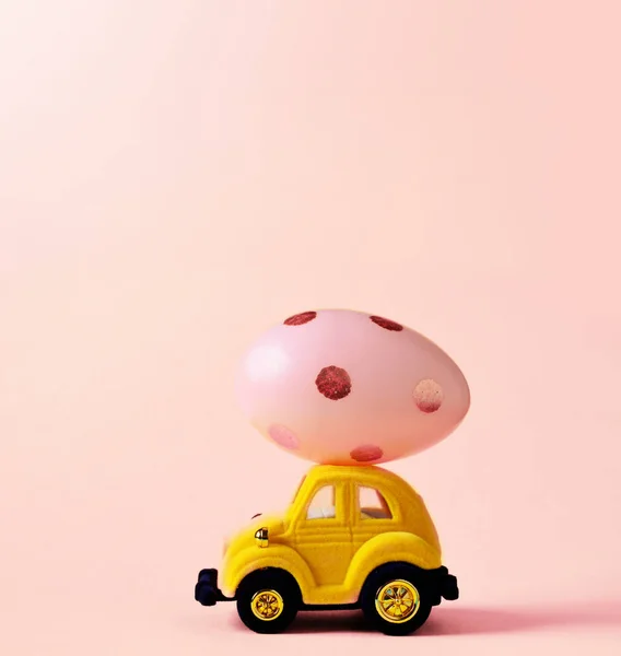 イースターエッグとハッピー イースターの日の概念 ピンクの背景でおもちゃの車 — ストック写真