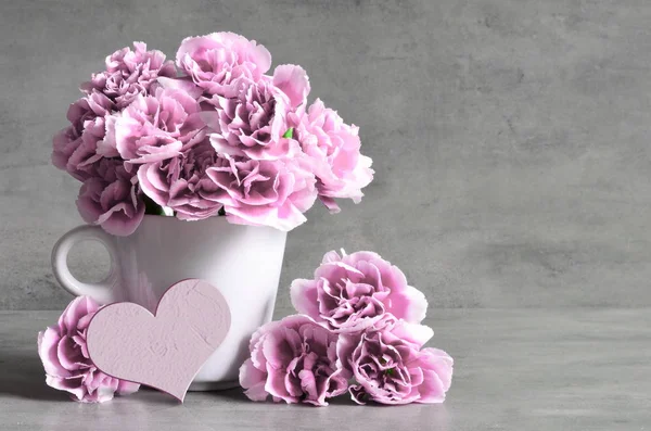 Fleurs oeillet rose en tasse et coeur sur fond gris . — Photo